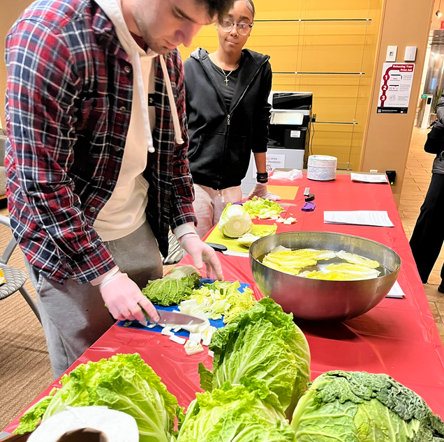 To show the student preparing the ingredients for the napa cabbage. Aiden and another student are cutting the napa cabbage.